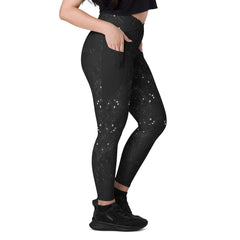 Woman wearing black crossover snake print leggings with pockets.