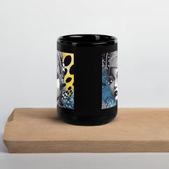 Graphic Guru Black Glossy Mug on a desk with books and a laptop.